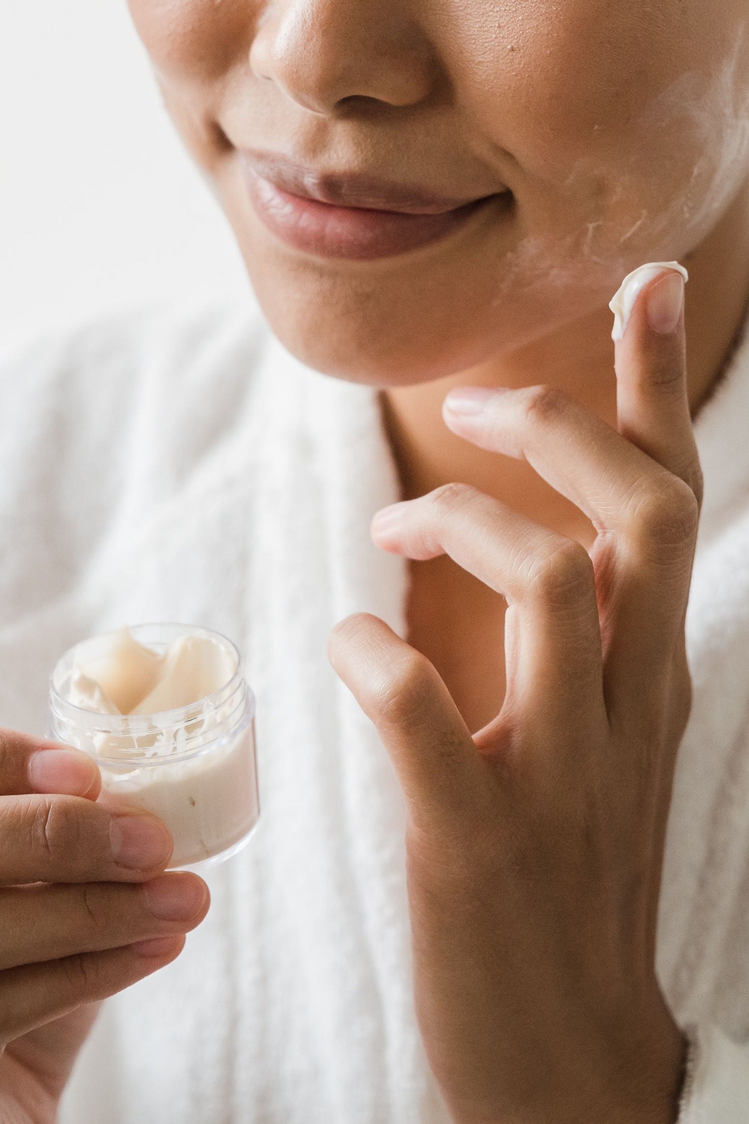 Close-up of fingertips applying moisturizing cream to skin in soft, warm natural light
